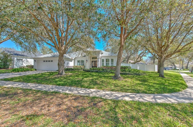 view of front of home featuring a garage, concrete driveway, stucco siding, fence, and a front yard