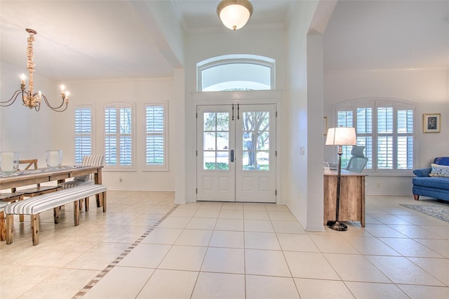 foyer featuring tile patterned flooring, baseboards, french doors, ornamental molding, and an inviting chandelier