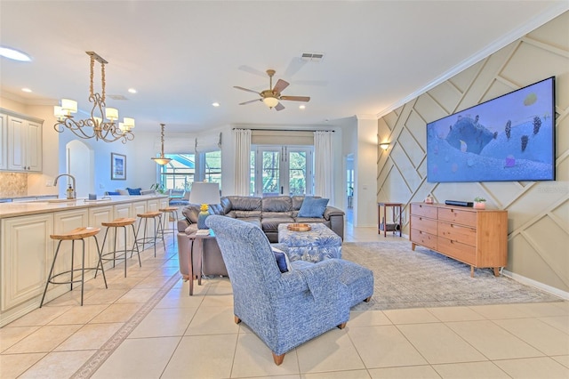 living room featuring arched walkways, light tile patterned floors, recessed lighting, visible vents, and ornamental molding