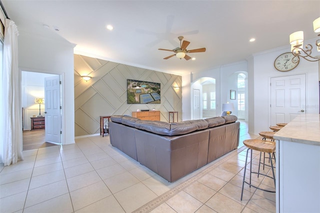 living room with light tile patterned floors, arched walkways, an accent wall, ornamental molding, and recessed lighting