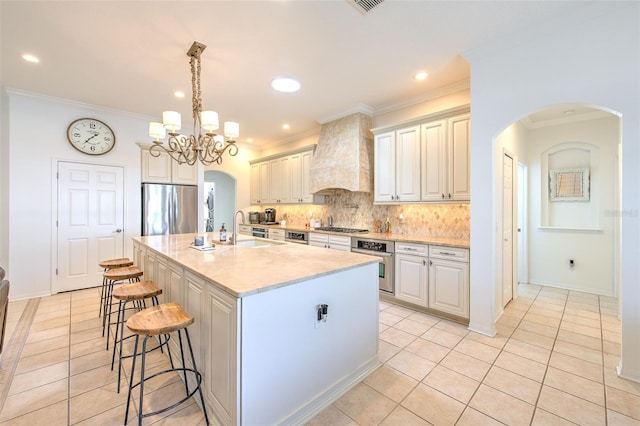 kitchen with arched walkways, a breakfast bar area, stainless steel appliances, backsplash, and premium range hood