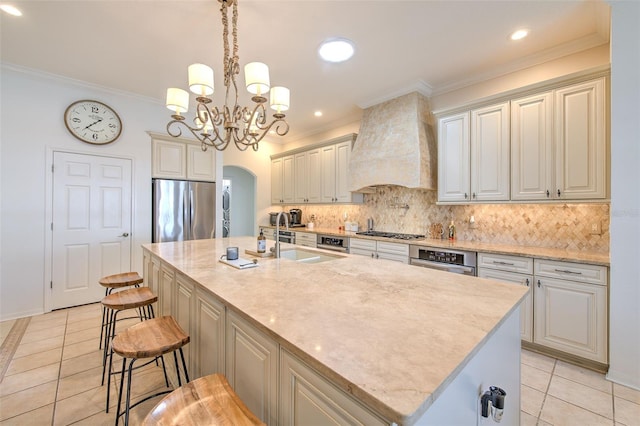 kitchen with arched walkways, stainless steel appliances, tasteful backsplash, a sink, and premium range hood