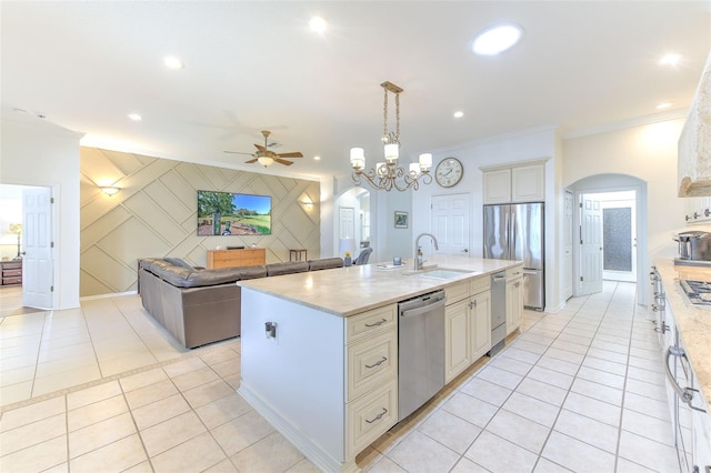 kitchen featuring arched walkways, appliances with stainless steel finishes, an accent wall, open floor plan, and a sink