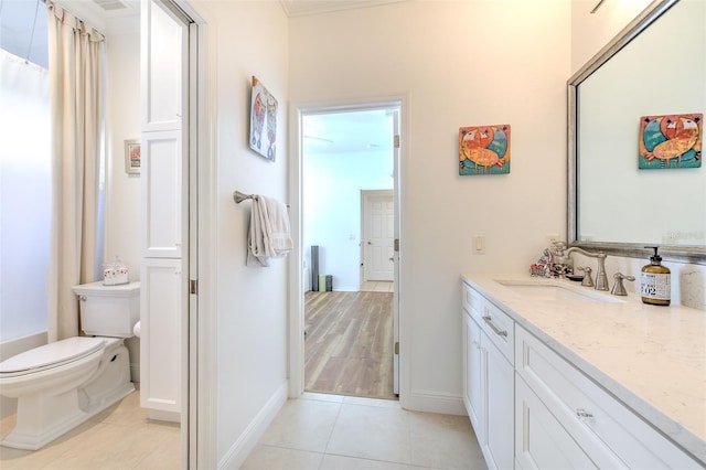 bathroom with toilet, vanity, baseboards, and tile patterned floors