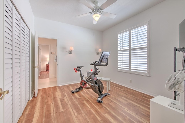 workout room featuring baseboards, ceiling fan, and light wood-style floors