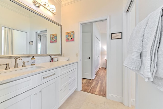 bathroom featuring baseboards, vanity, ornamental molding, and tile patterned floors