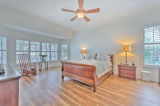 bedroom with light wood finished floors, ornamental molding, and a decorative wall