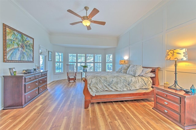 bedroom with light wood-style flooring, a decorative wall, and crown molding