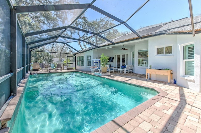 view of pool with glass enclosure, a patio, and ceiling fan