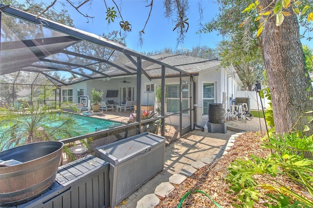 back of property featuring a ceiling fan, an outdoor pool, glass enclosure, and a patio