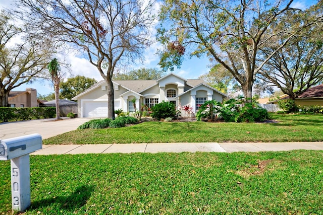 ranch-style home featuring stucco siding, concrete driveway, fence, a garage, and a front lawn