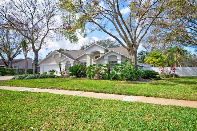 view of front of home featuring a front lawn, an attached garage, fence, and stucco siding