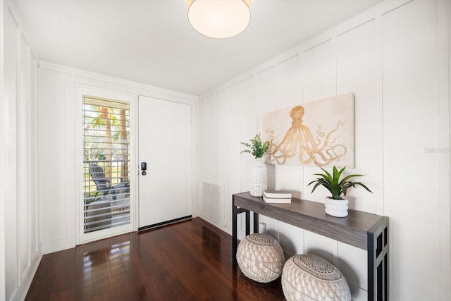 doorway featuring visible vents, a decorative wall, and dark wood finished floors