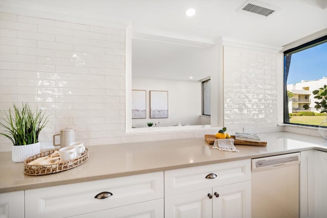 kitchen with white dishwasher, visible vents, white cabinets, light countertops, and tasteful backsplash