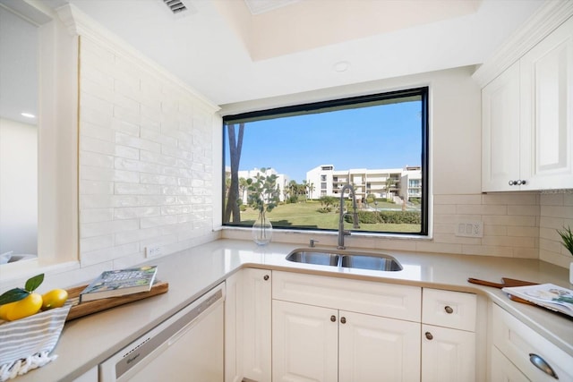 kitchen with light countertops, white dishwasher, a sink, and white cabinetry