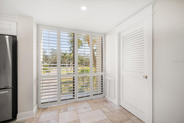 doorway featuring baseboards, stone tile flooring, visible vents, and recessed lighting