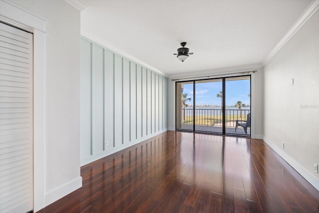 empty room featuring dark wood-style flooring, crown molding, and baseboards