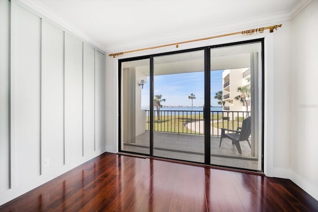 spare room with dark wood-style floors, a water view, crown molding, and baseboards