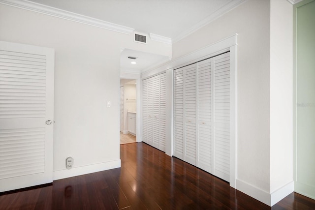 unfurnished bedroom with dark wood-type flooring, visible vents, ornamental molding, and baseboards