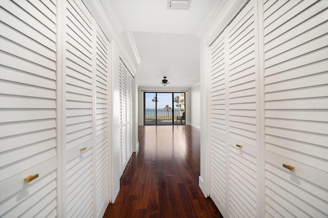 hall with dark wood-type flooring, visible vents, and crown molding