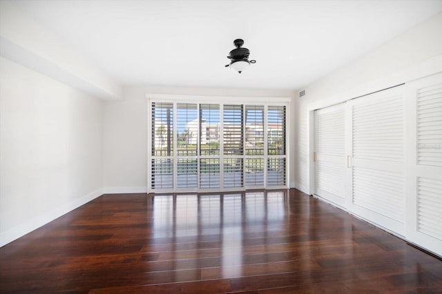 spare room with dark wood-style floors and baseboards