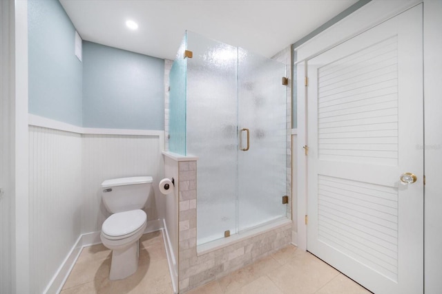 bathroom featuring tile patterned flooring, a wainscoted wall, toilet, and an enclosed shower