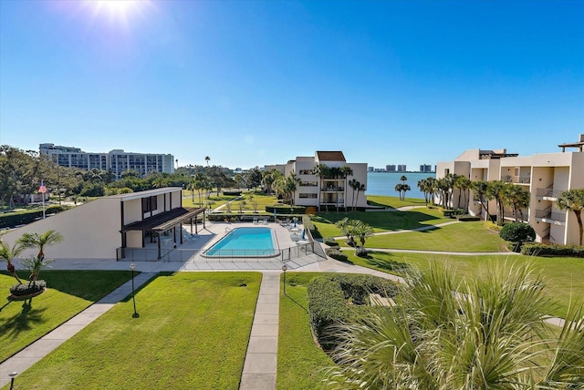 pool with a water view, a patio area, and a yard