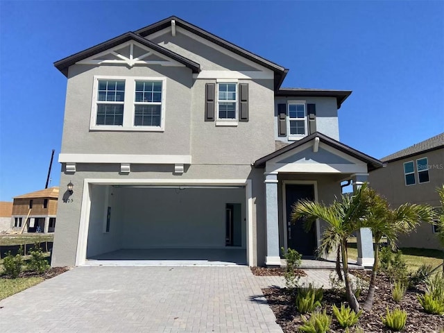 view of front of home featuring stucco siding, decorative driveway, and a garage