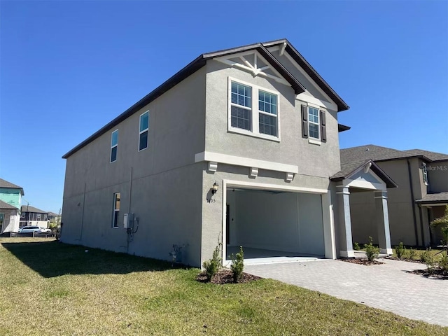 view of side of home with a yard, stucco siding, decorative driveway, and a garage