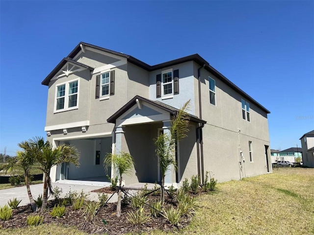 view of front of home featuring stucco siding, driveway, a front yard, and a garage