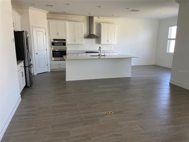 kitchen with a kitchen island with sink, stainless steel appliances, dark wood-type flooring, white cabinets, and wall chimney exhaust hood