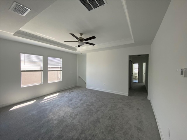 carpeted spare room with visible vents, baseboards, a raised ceiling, and a ceiling fan