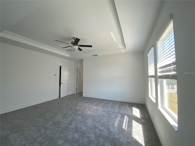 empty room featuring visible vents, a raised ceiling, carpet flooring, baseboards, and ceiling fan