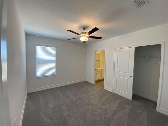 unfurnished bedroom with a closet, visible vents, dark carpet, and baseboards