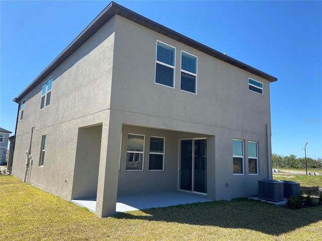 rear view of house featuring stucco siding, a patio, a yard, and central AC unit