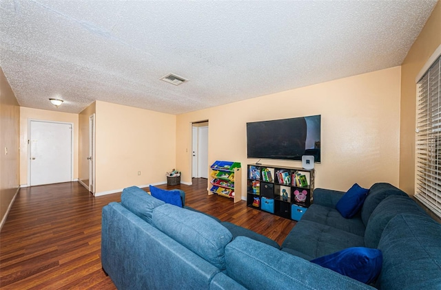 living area featuring baseboards, a textured ceiling, visible vents, and wood finished floors