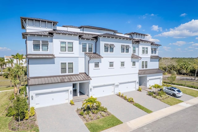 townhome / multi-family property with metal roof, decorative driveway, a standing seam roof, and an attached garage