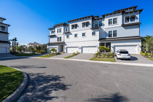 view of front of property featuring driveway, an attached garage, a residential view, and stucco siding