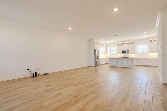 unfurnished living room with light wood finished floors, recessed lighting, and baseboards