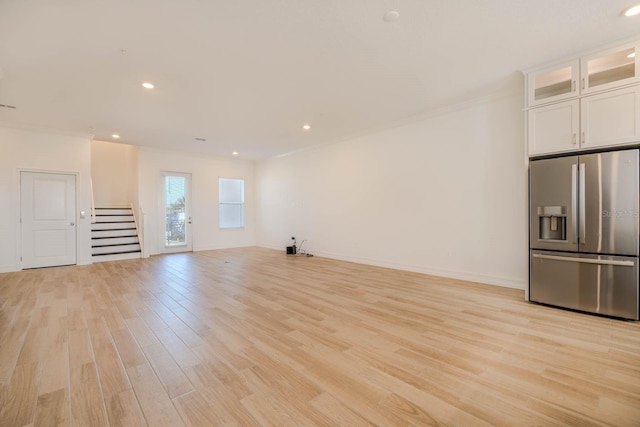 unfurnished living room with light wood finished floors, stairway, baseboards, and crown molding