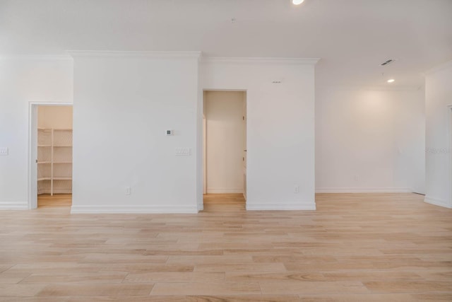 empty room featuring ornamental molding, light wood-style flooring, and baseboards