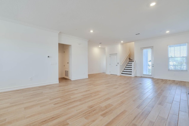 spare room featuring stairs, crown molding, baseboards, and light wood-style floors