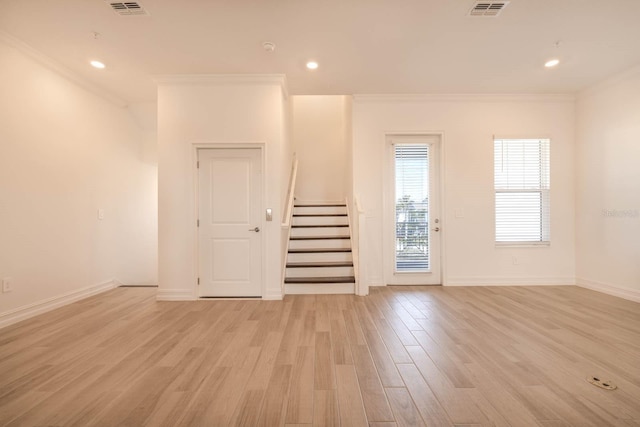 empty room featuring visible vents, baseboards, stairway, ornamental molding, and light wood-type flooring