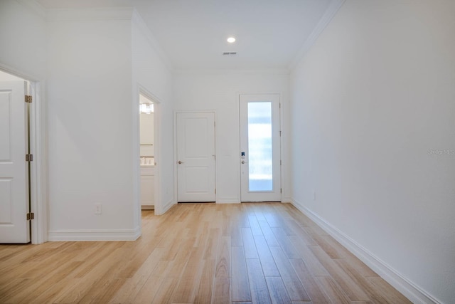 entrance foyer with ornamental molding, light wood finished floors, visible vents, and baseboards