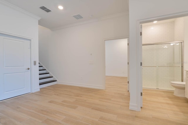 basement featuring light wood-style floors, visible vents, crown molding, and stairs