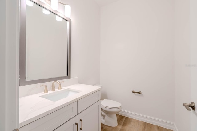 bathroom featuring vanity, wood finished floors, toilet, and baseboards