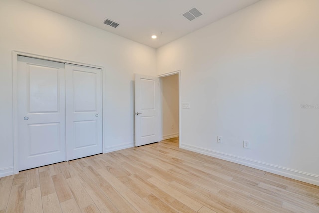 unfurnished bedroom featuring light wood-type flooring, a closet, visible vents, and baseboards