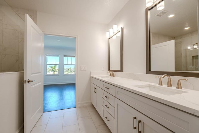 full bathroom with double vanity, baseboards, visible vents, and a sink