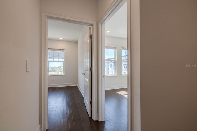 corridor featuring dark wood-style floors and baseboards