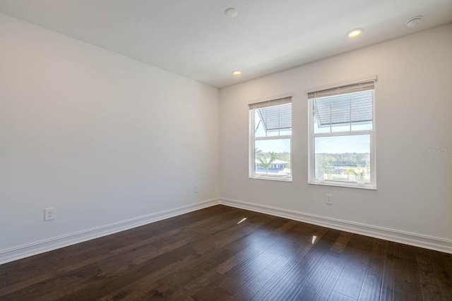 unfurnished room featuring dark wood-type flooring, recessed lighting, and baseboards